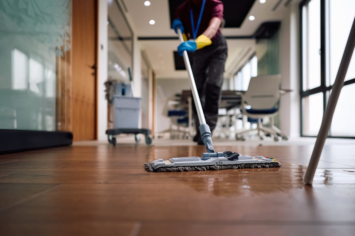 Close up of janitor using mop while cleaning office floors